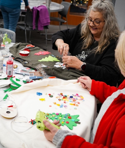 photo of two people decorating their own ugly Christmas sweaters during last year's party