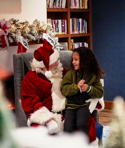 a photo of a little girl sitting on Santa's lap and talking to him