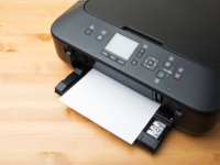 Printer sitting on a wooden table while a paper prints out