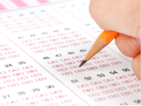 Hand holding a pencil filling in a test scantron sheet