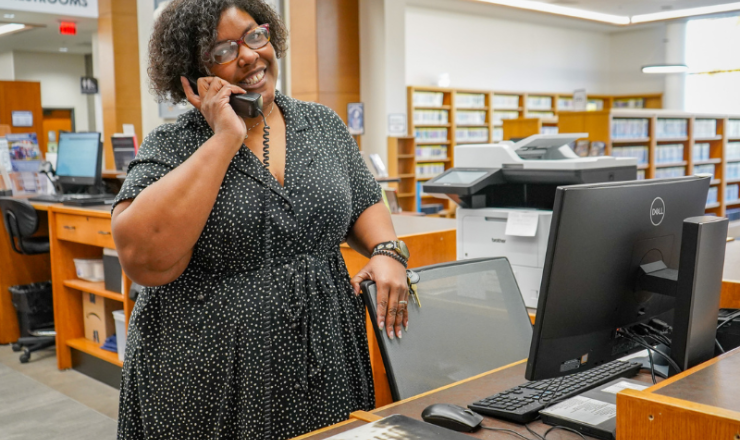 Librarian smiling while answering a call at the circulation desk