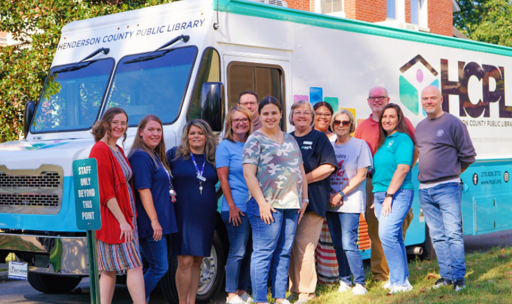 A group of librarians smiling in front of the HCPL Mobile Library