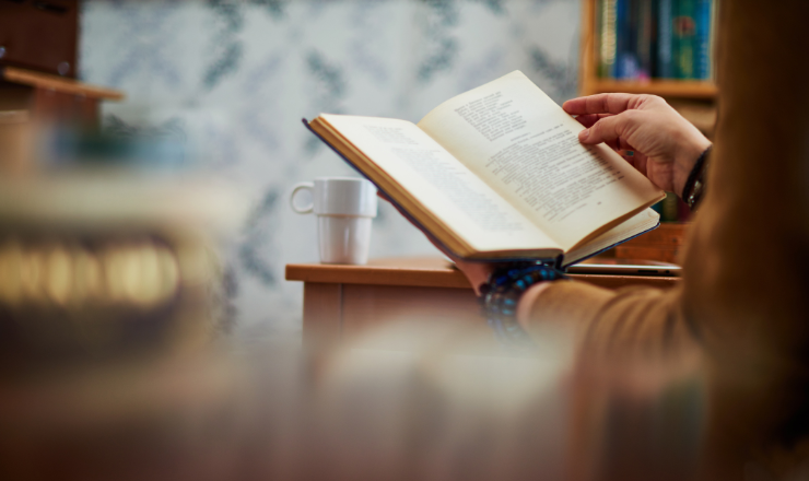 Photo of someone reading a book with a cup of coffee next to them